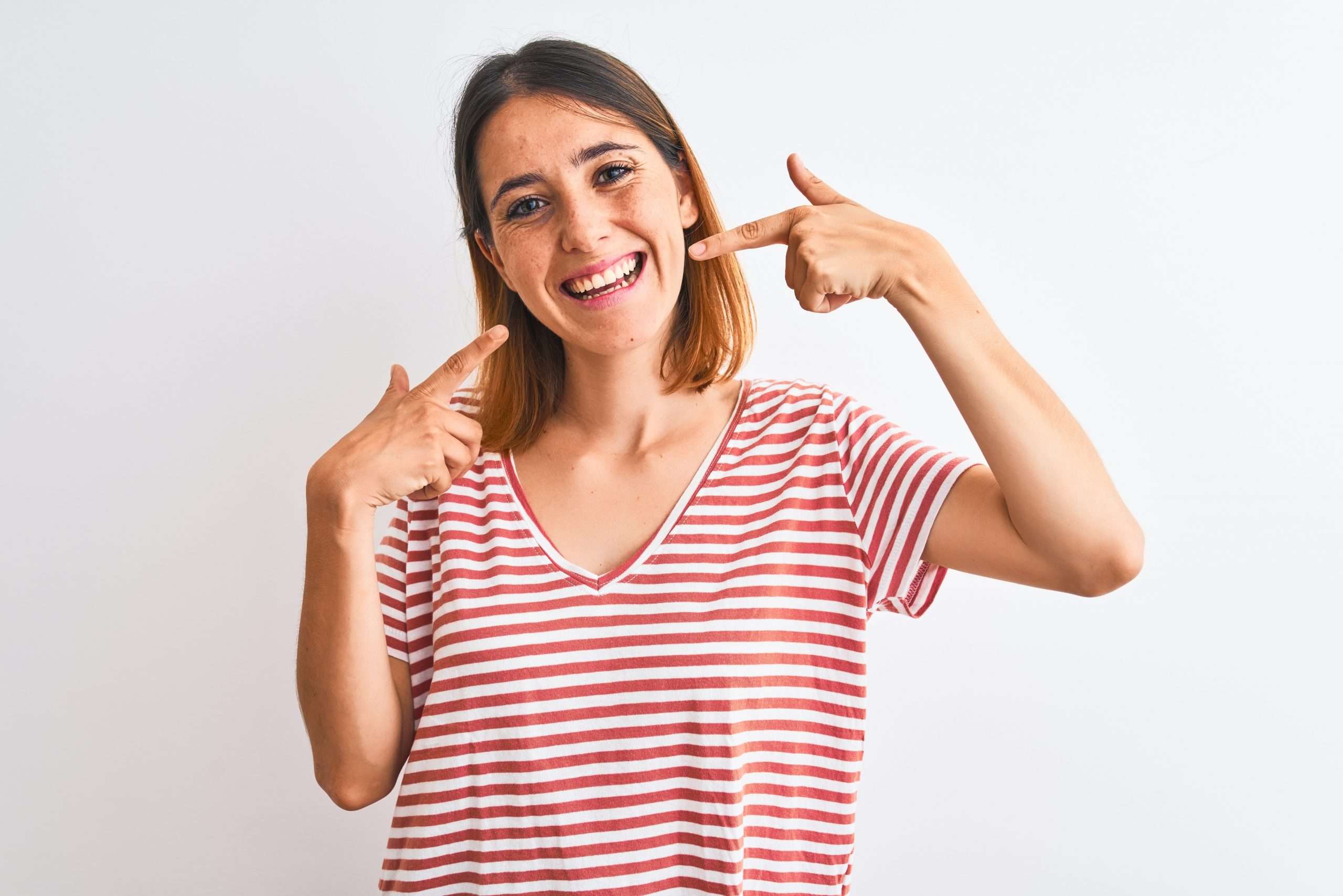 woman smiling and pointing to teeth